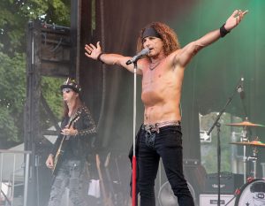 rock singer singing at microphone with arms outstretched