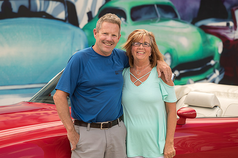 portrait of jack and tammy stinson standing in front of a red, 1971 Pontiac Le Mans convertible